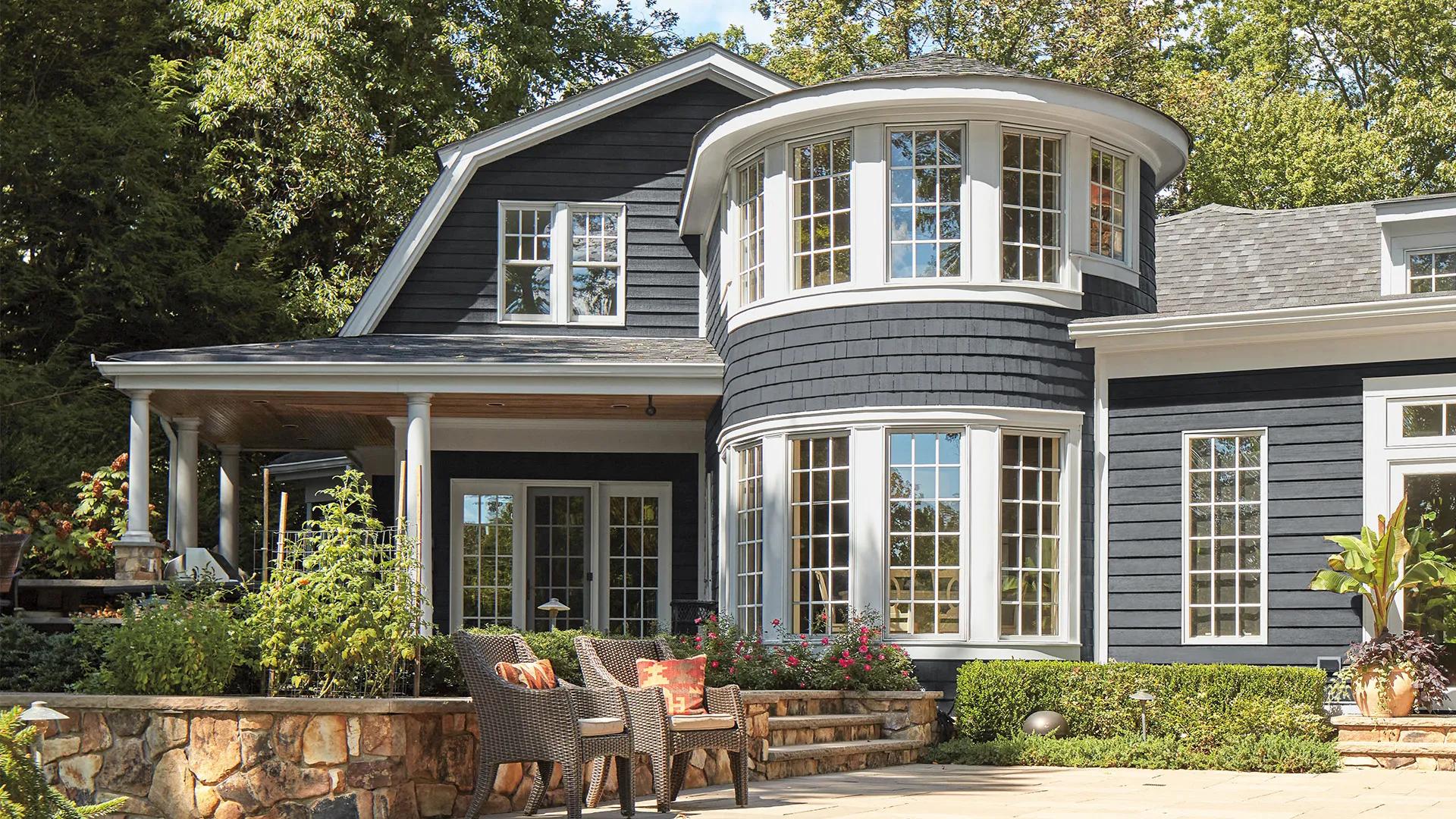 Deep gray home exterior with white trim and a poolside patio